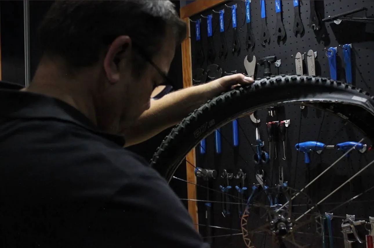 Neil checking a wheel in front of the workshop tool wall at Neilson Cycles.